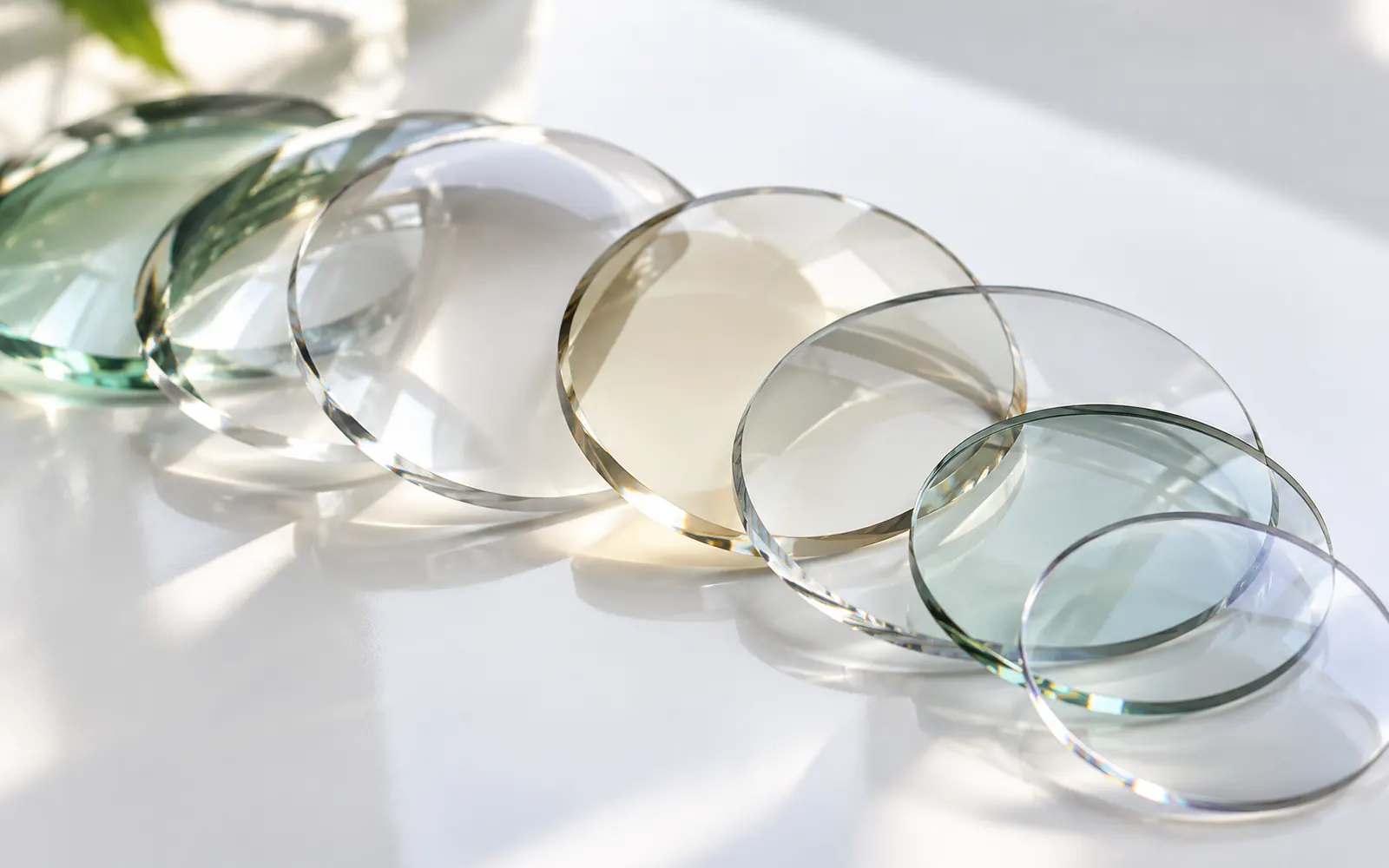 Close de várias lentes sobre uma superfície branca, com reflexos suaves.